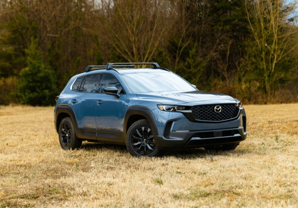 Blue Mazda CX-50 Hybrid parked in a grassy field