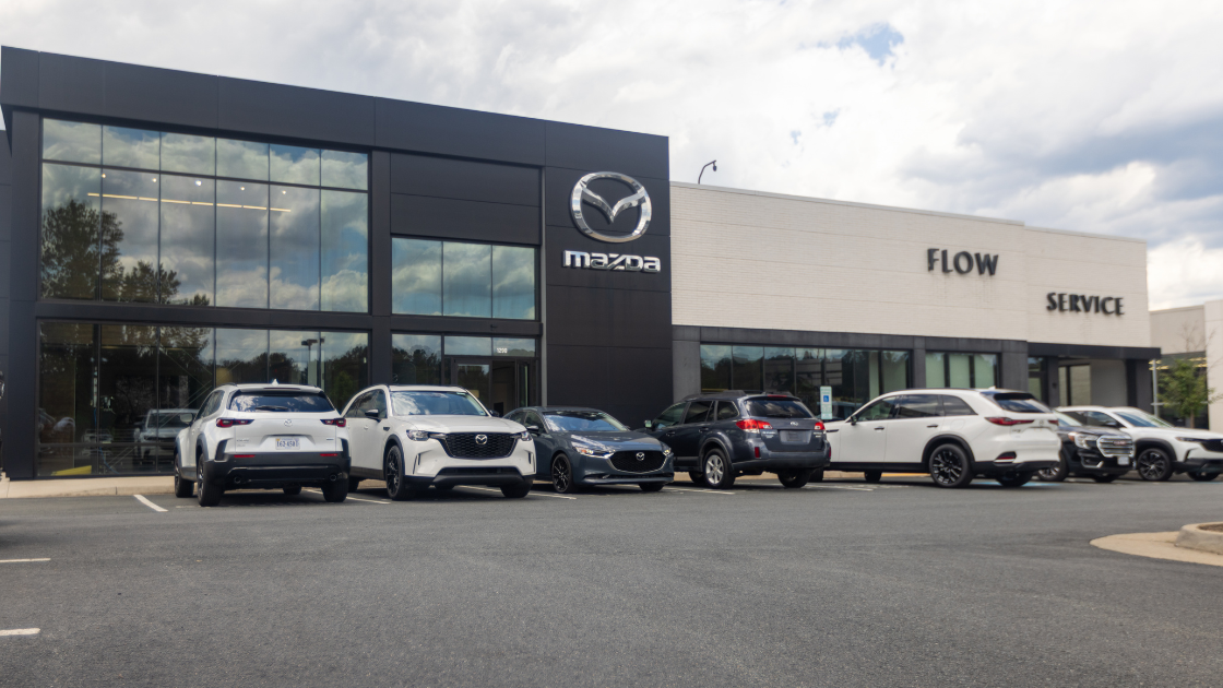 A lineup of Mazda cars parked in front of the Flow Mazda of Charlottesville dealership