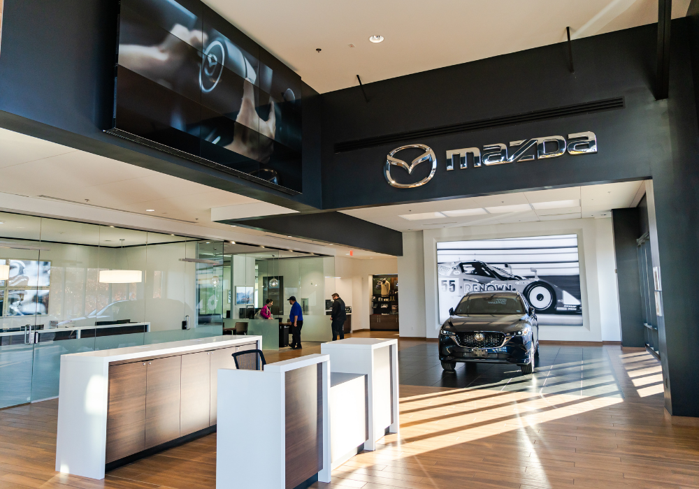 Interior of the Flow Mazda of Charlottesville dealership with a car parked in the showroom