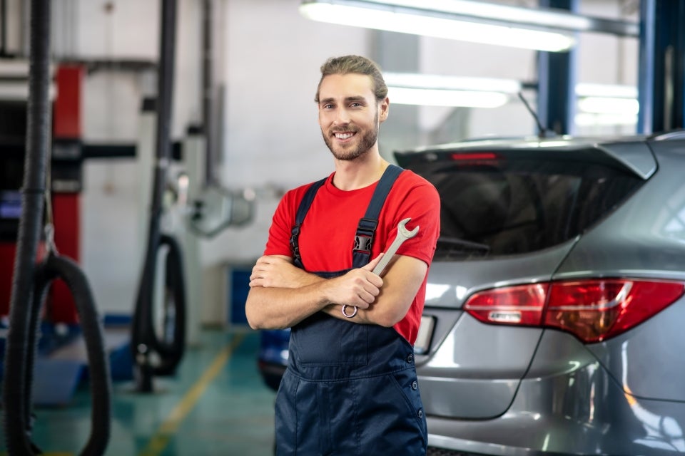 A service expert holding a wench in a dealership workshop